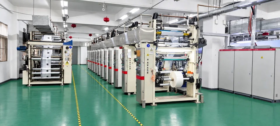 A wide workshop view showing rows of roll-fed production equipment